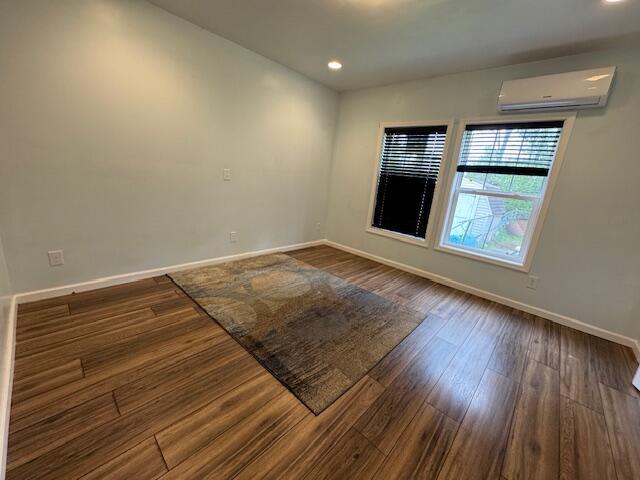 205 Wren Rd, Sturgis, MI 49091 - empty room with an AC wall unit, baseboards, dark wood-type flooring, and recessed lighting