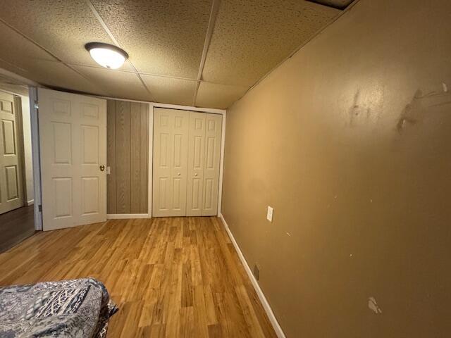 205 Wren Rd, Sturgis, MI 49091 - unfurnished bedroom with baseboards, light wood-type flooring, a paneled ceiling, and a closet