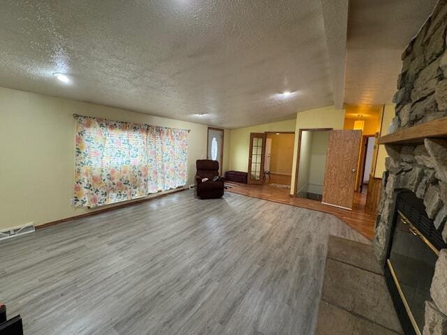 205 Wren Rd, Sturgis, MI 49091 - unfurnished living room with wood finished floors, a textured ceiling, a fireplace, lofted ceiling, and baseboards