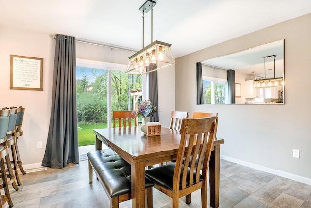 dining area featuring light wood finished floors, baseboards, and a chandelier