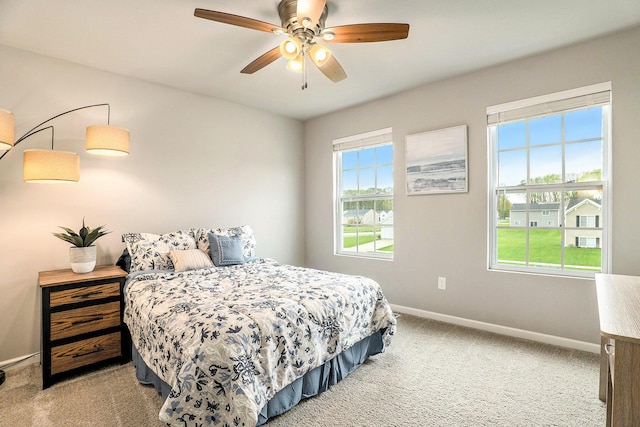 bedroom featuring light carpet, baseboards, and ceiling fan
