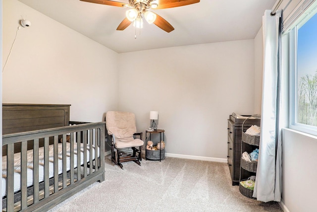 bedroom with carpet, baseboards, a ceiling fan, and a nursery area