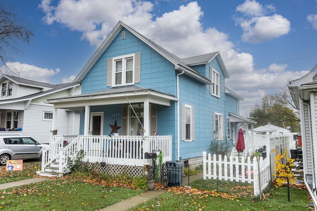 bungalow-style home with covered porch, fence, and roof with shingles