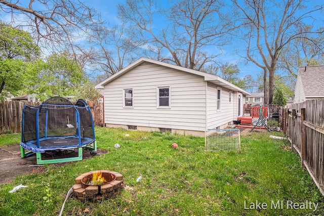 view of property exterior featuring a trampoline, a deck, and an outdoor fire pit