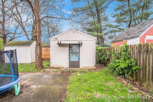 view of shed with a trampoline and a fenced backyard