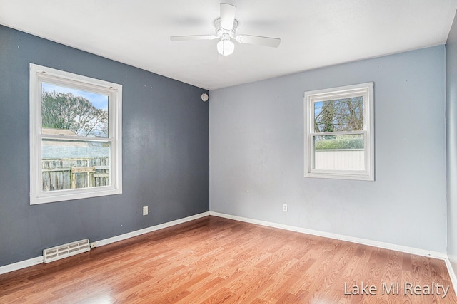 empty room with light wood finished floors, a ceiling fan, and baseboards