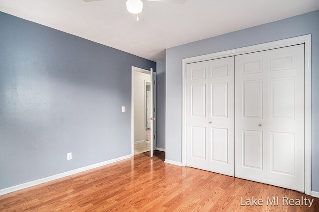 unfurnished bedroom featuring light wood-type flooring, a closet, baseboards, and ceiling fan