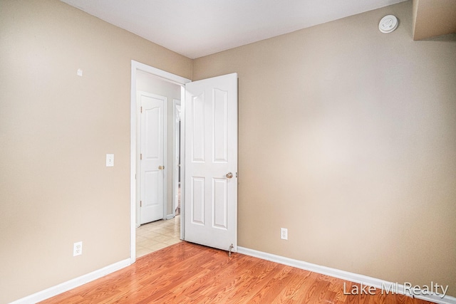 spare room with baseboards, a smoke detector, and light wood-type flooring