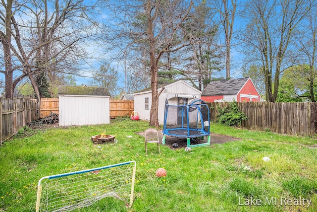 view of yard with a storage shed, an outdoor fire pit, an outdoor structure, and a trampoline