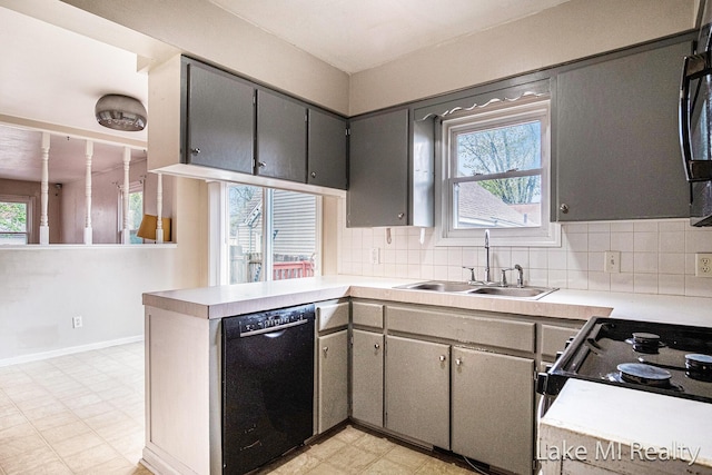 kitchen featuring black appliances, a sink, light flooring, a peninsula, and light countertops