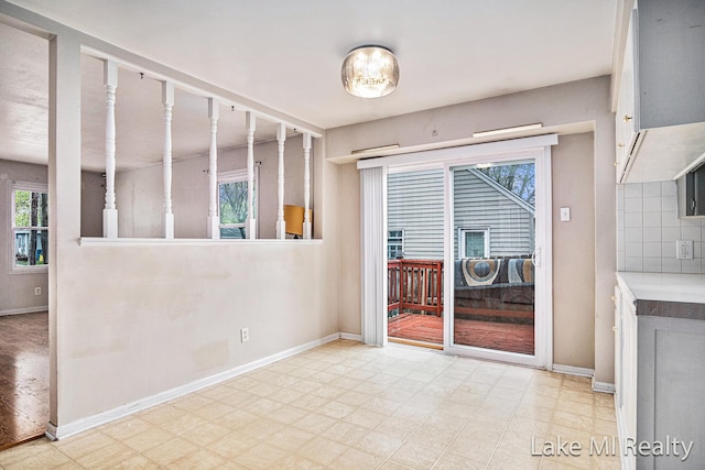empty room featuring plenty of natural light, tile patterned floors, and baseboards