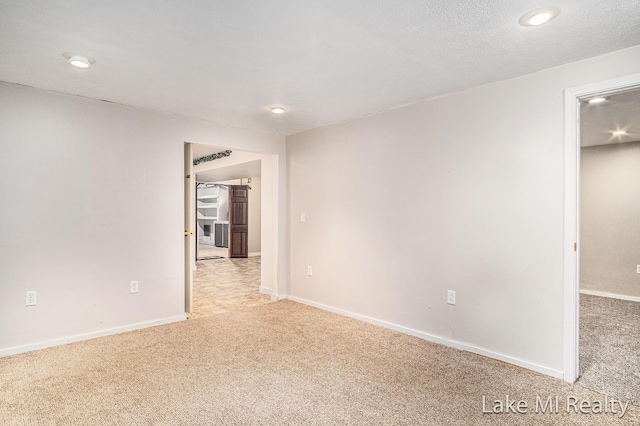 spare room featuring light colored carpet, recessed lighting, and baseboards