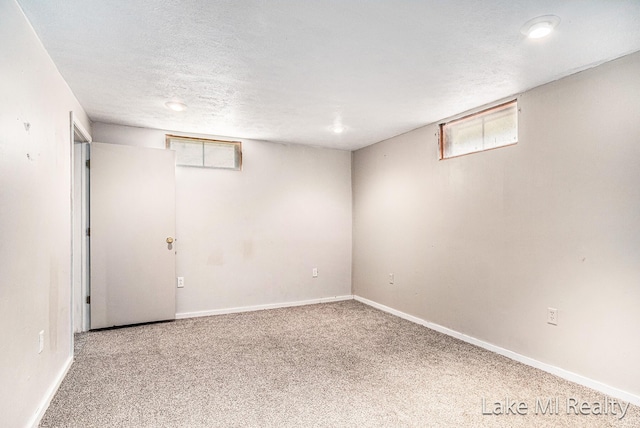 basement featuring carpet floors, baseboards, and a textured ceiling
