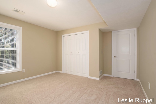 unfurnished bedroom with light carpet, a closet, and baseboards