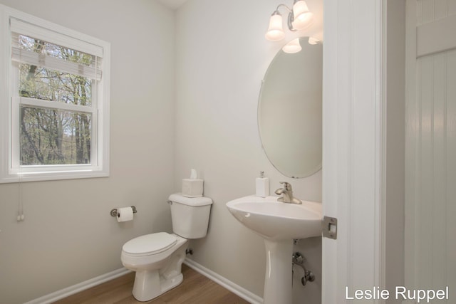 bathroom featuring baseboards, wood finished floors, and toilet