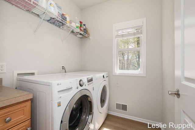 washroom featuring washer and clothes dryer, light wood-style flooring, and baseboards
