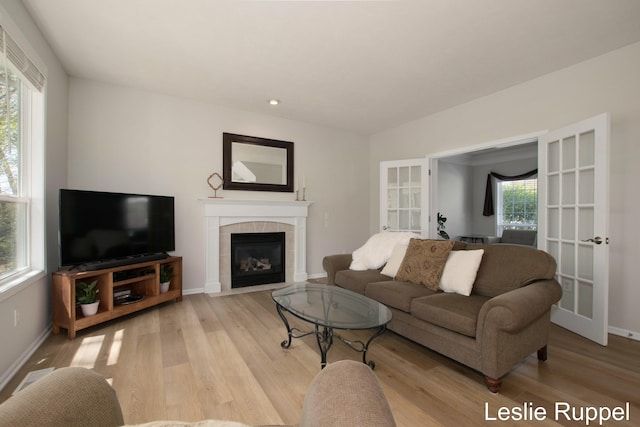 living area featuring light wood-style flooring, a fireplace, and baseboards