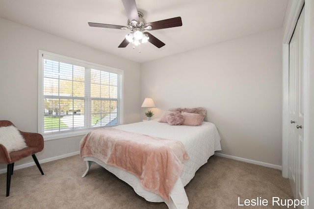 bedroom featuring a closet, light carpet, baseboards, and a ceiling fan