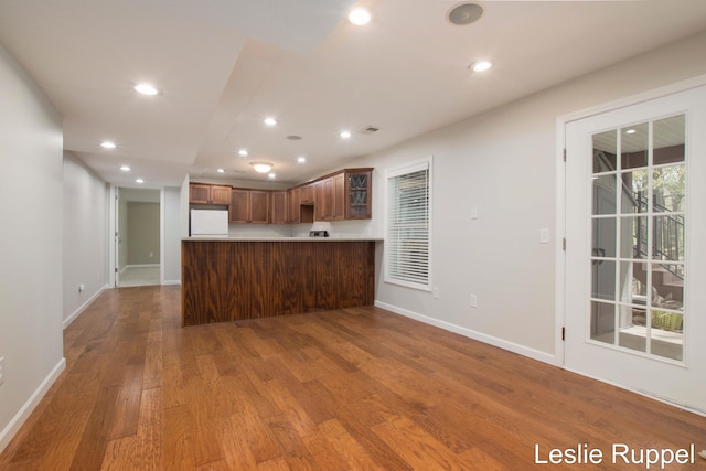 kitchen featuring freestanding refrigerator, wood finished floors, baseboards, recessed lighting, and a peninsula