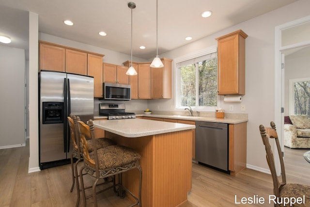 kitchen with appliances with stainless steel finishes, light wood finished floors, a sink, a kitchen island, and recessed lighting