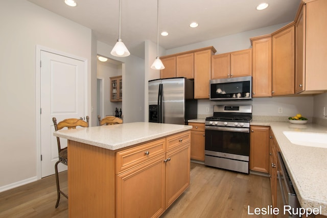 kitchen with appliances with stainless steel finishes, a breakfast bar, light wood-type flooring, recessed lighting, and hanging light fixtures