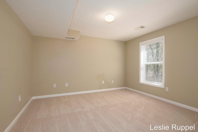carpeted spare room with baseboards and a wall mounted AC
