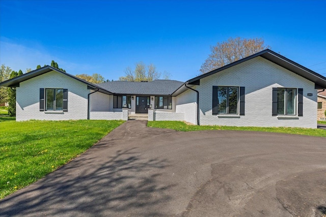 view of front of property featuring brick siding, a front yard, and driveway