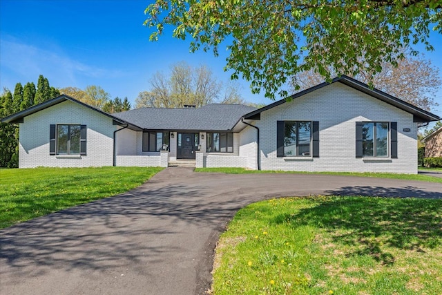 ranch-style home featuring brick siding, asphalt driveway, and a front yard