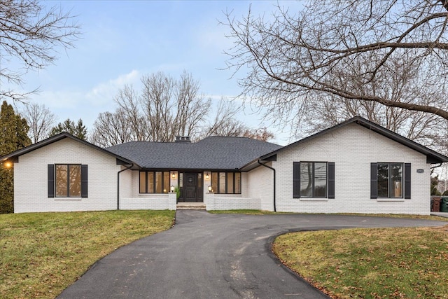 view of front of property featuring brick siding, driveway, and a front yard