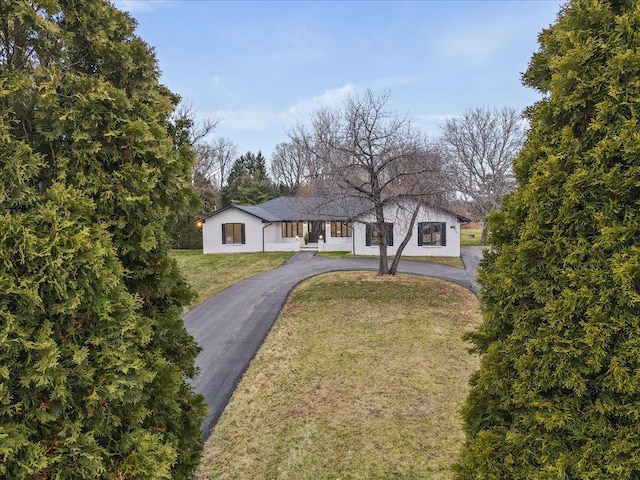 view of front of home featuring asphalt driveway and a front lawn
