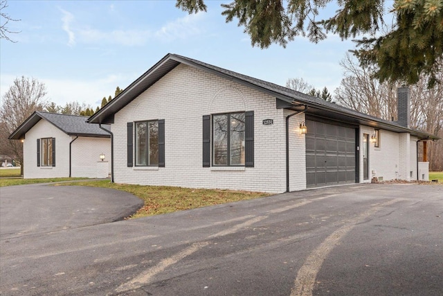 view of home's exterior featuring driveway, an attached garage, and brick siding