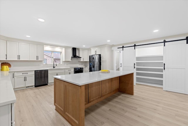 kitchen with black dishwasher, fridge with ice dispenser, wall chimney range hood, a barn door, and recessed lighting