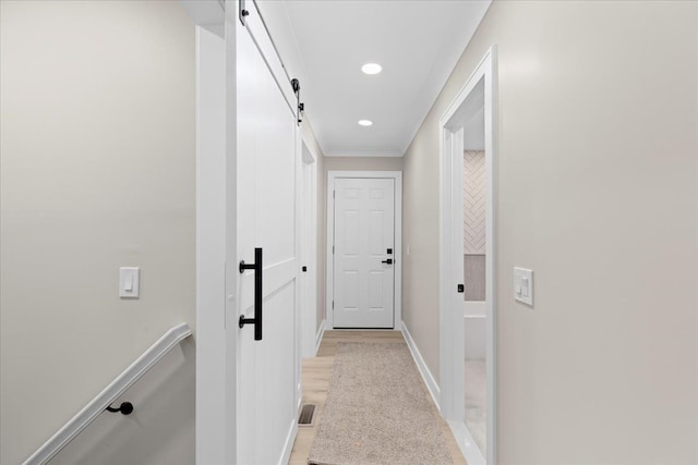 corridor with a barn door, baseboards, and recessed lighting