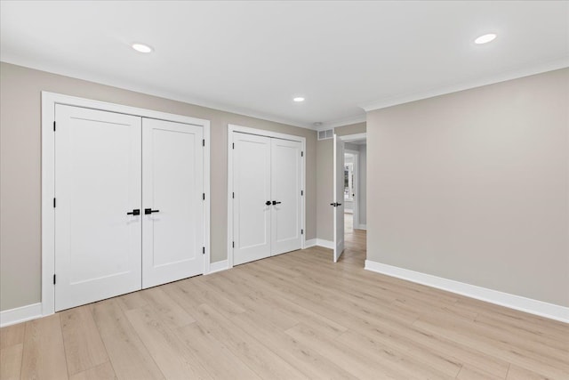 unfurnished bedroom featuring two closets, light wood-type flooring, recessed lighting, baseboards, and ornamental molding