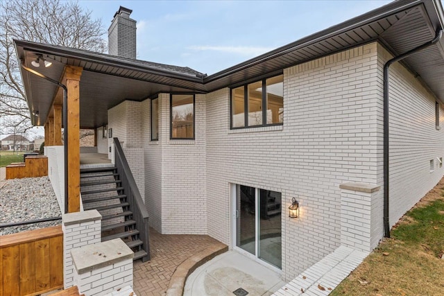 view of home's exterior featuring a chimney, covered porch, and brick siding