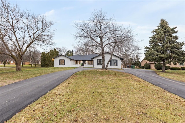 view of front of property featuring asphalt driveway, a front lawn, and stucco siding