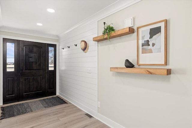foyer entrance featuring light wood-type flooring, baseboards, crown molding, wood walls, and recessed lighting