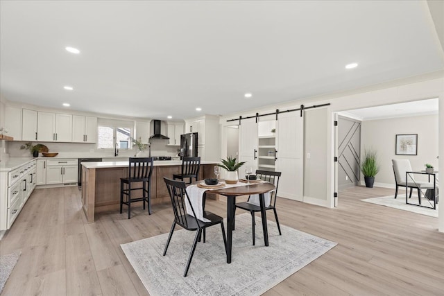 dining room featuring a barn door, recessed lighting, light wood-type flooring, and baseboards