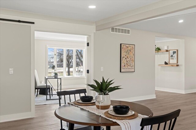 dining room featuring light wood finished floors, baseboards, a barn door, and recessed lighting