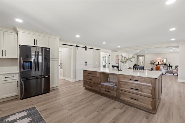 kitchen with black fridge with ice dispenser, a barn door, light wood finished floors, light countertops, and recessed lighting