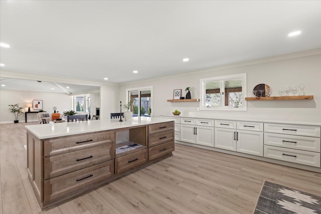 kitchen featuring open shelves, ornamental molding, light wood finished floors, a kitchen island, and light countertops