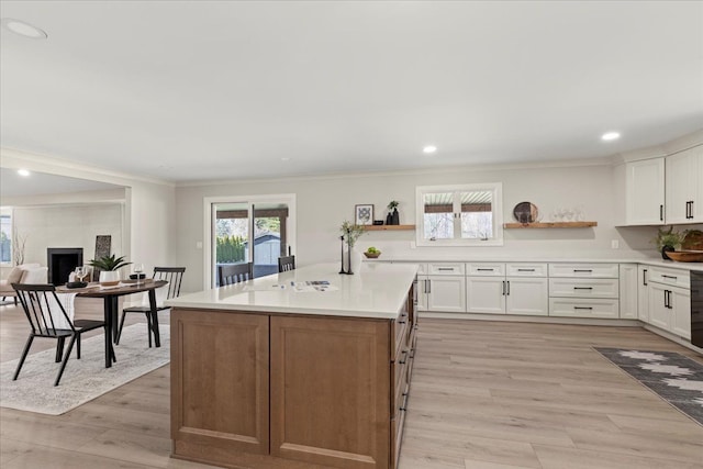 kitchen with open shelves, ornamental molding, white cabinetry, light wood-style flooring, and light countertops