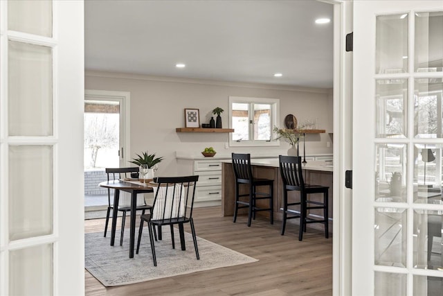 dining room featuring ornamental molding, wood finished floors, healthy amount of natural light, and recessed lighting