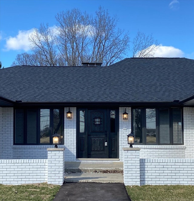 property entrance with brick siding and a shingled roof