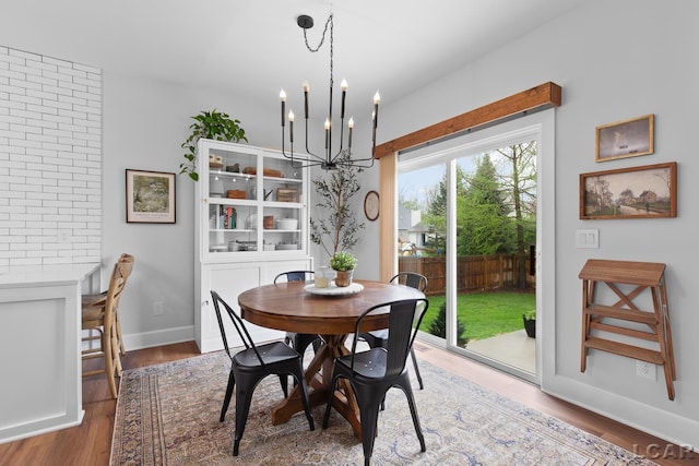 dining area with a chandelier, wood finished floors, and baseboards