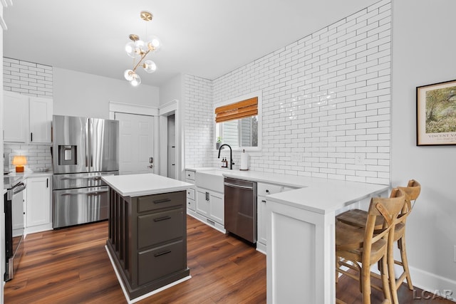 kitchen with stainless steel appliances, decorative backsplash, white cabinets, light countertops, and dark wood-type flooring
