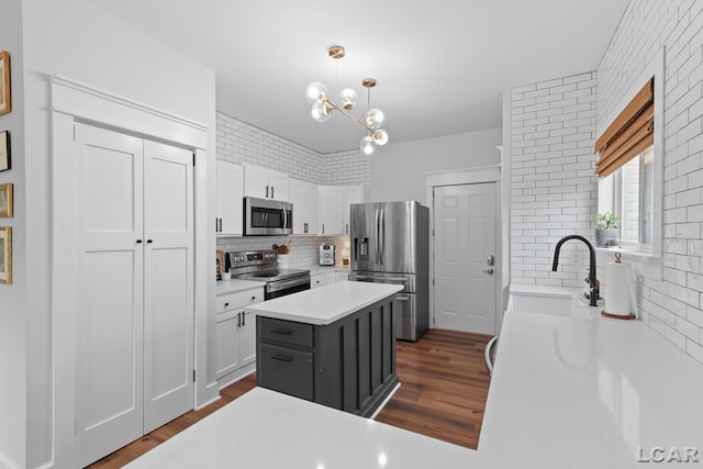 kitchen featuring appliances with stainless steel finishes, a sink, light countertops, and dark wood-type flooring