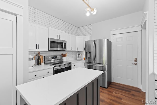 kitchen with appliances with stainless steel finishes, light countertops, white cabinets, a center island, and decorative backsplash