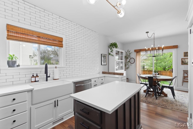 kitchen with a chandelier, a sink, backsplash, light countertops, and dark wood-type flooring