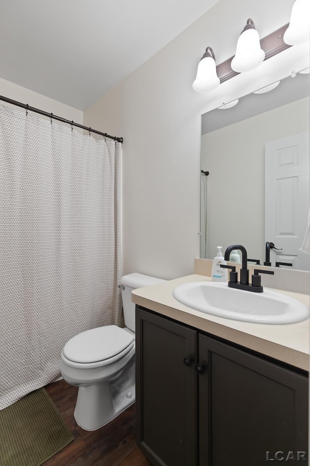 bathroom with wood finished floors, toilet, vanity, and a shower with shower curtain